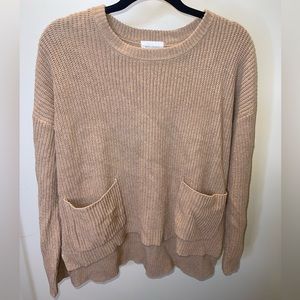 Light brown knitted sweater. Slit sides w/front pockets. Size large.